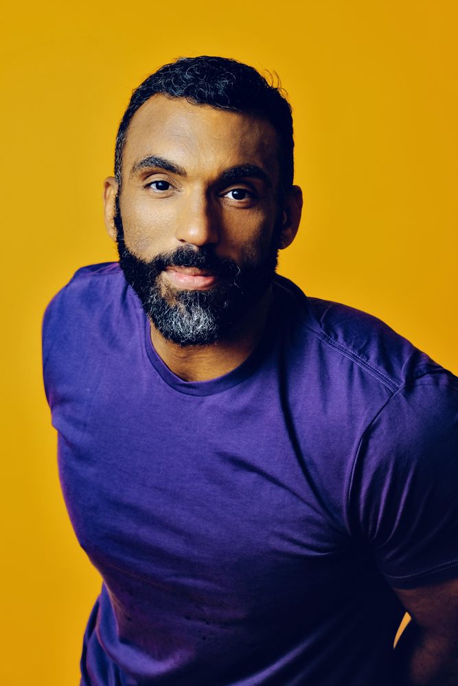 Confident Black man in yellow studio, vertical composition
