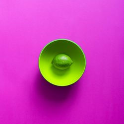 Lime in green bowl on purple background