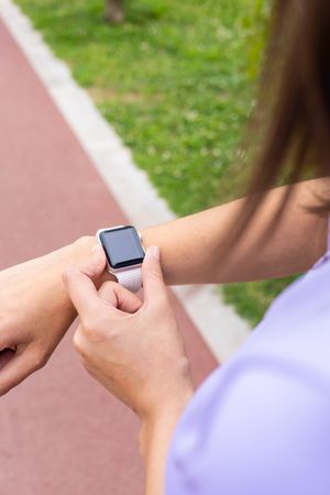 Woman checking a sport smartwatch for running workout outdoors