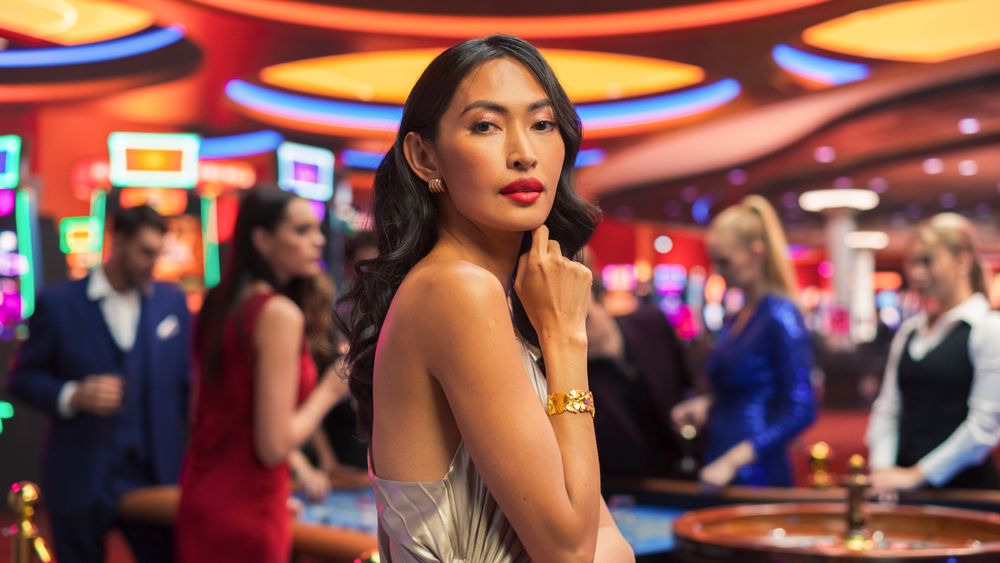 Young Asian Woman, Wearing an Elegant Silver Dress, Standing in a Modeling Pose in a Casino