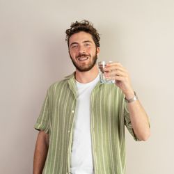 Happy young man holding a glass of fresh and pure water.