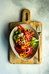 Top view of healthy salad with organic vegetables and chickpeas on wooden board