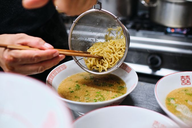 Crop person cooking ramen in kitchen