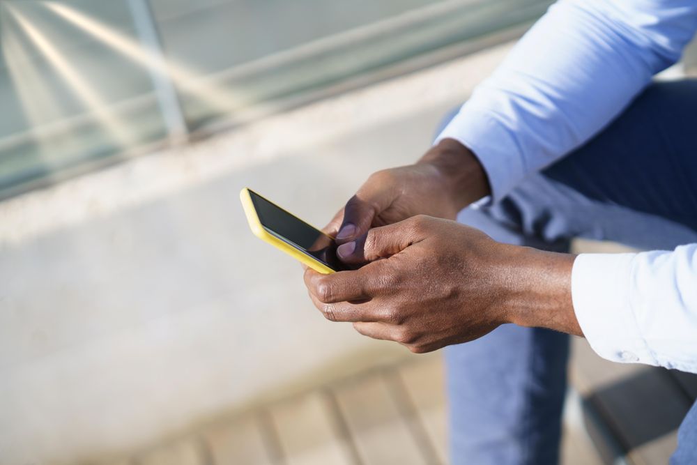 Close up of hands of a man holding a yellow phone