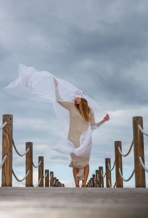 Woman with textile posing in air on footbridge