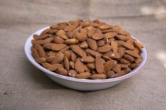 A Bowl of almonds on Jute fiber fabric