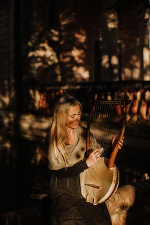Sensual female musician playing lyre in garden
