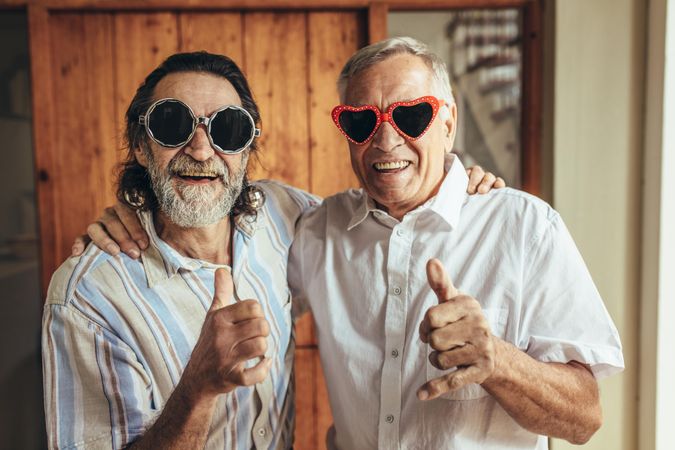 Happy men wearing funny sunglasses showing thumbs up