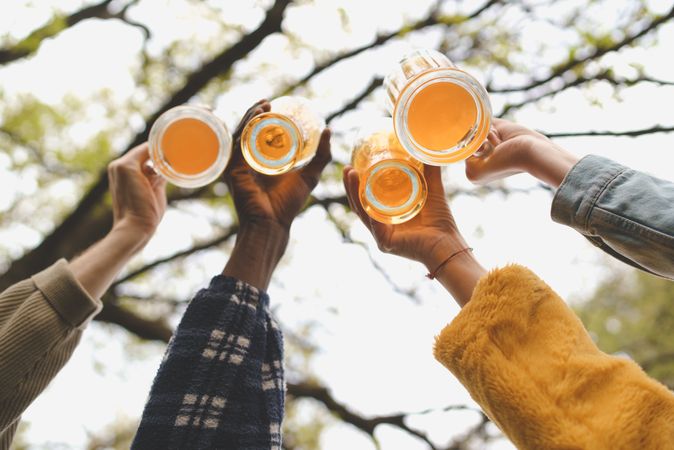 Bottom of beer glasses being clinked together by multi-ethnic friends