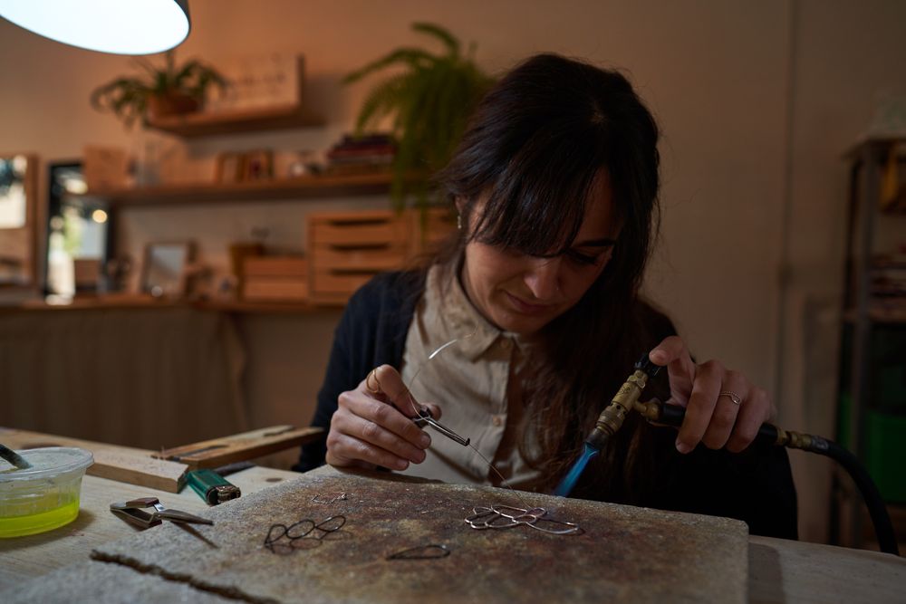 Female artisan with gas burner making handmade accessory