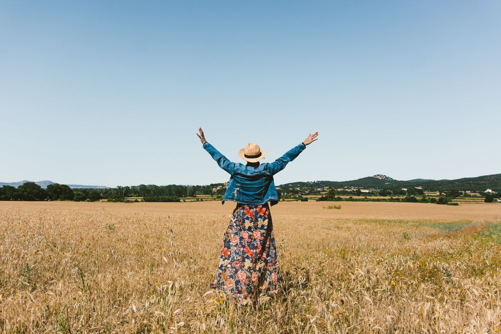 Female farmer with hat looking at her wheat crop.