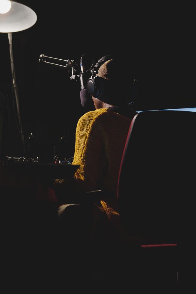 Unrecognizable Black woman in headset in dark broadcast studio