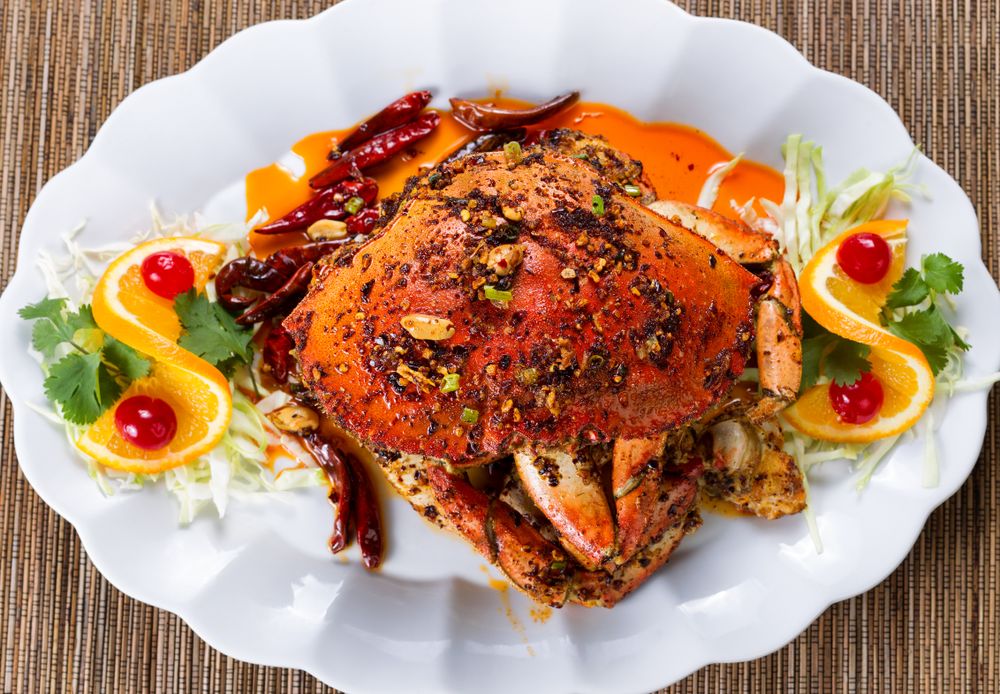 Whole cooked Dungeness crab with peanut sauce and spices on serving plate ready to eat