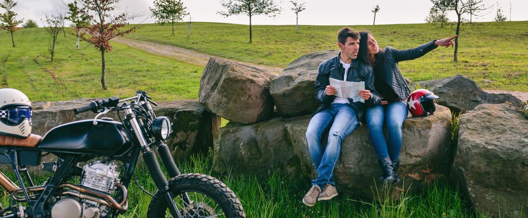 Couple sitting looking at a map with motorcycle