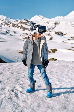 Boy in VR goggles in snowy mountains