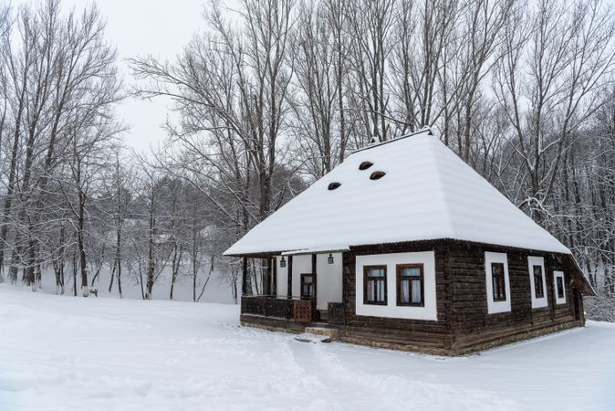 Winter scenery with an old Romanian traditional wooden house covered in deep snow