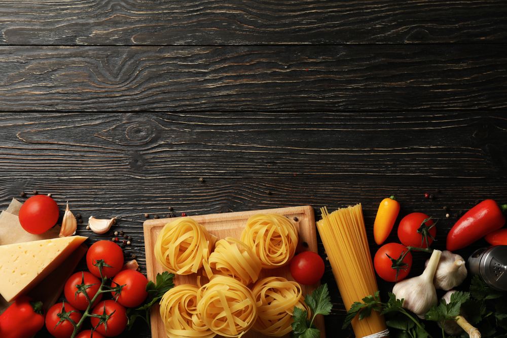 Composition with pasta and ingredients for cooking on wooden background, top view
