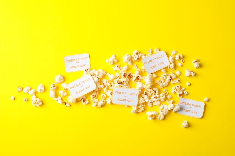 Flat lay composition with popcorn and tickets on yellow background
