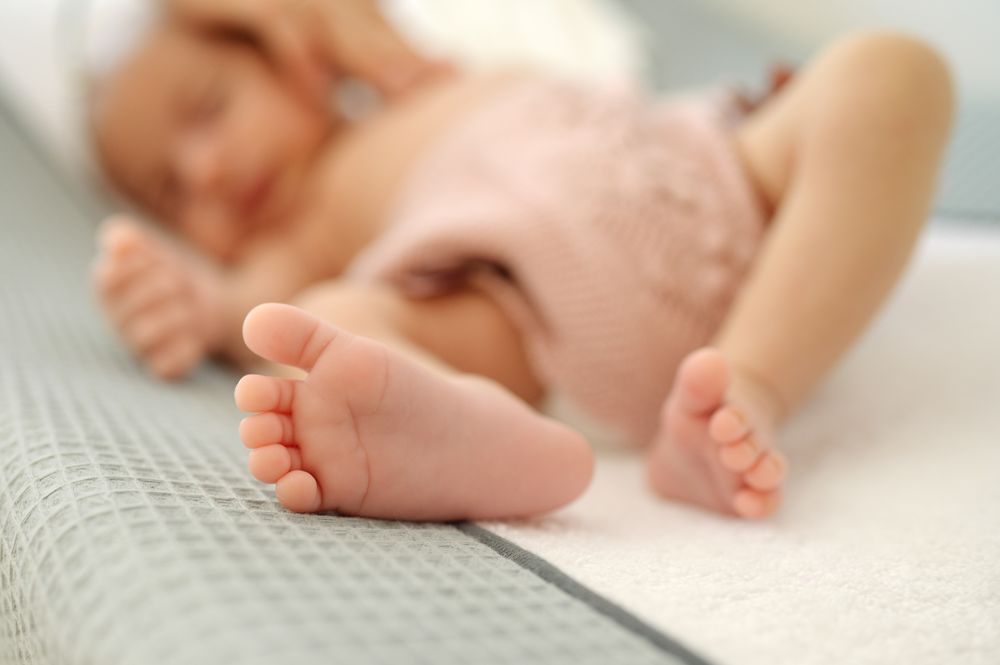 A close up of a baby laying on a bed