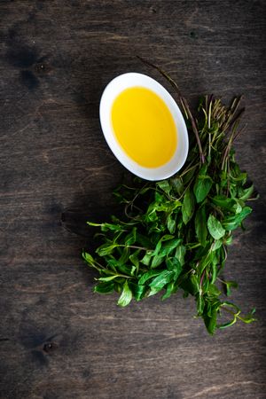Bowl of oil and herbs on wooden table