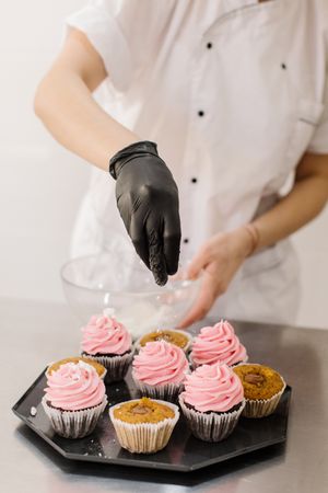 Chef adding sprinkles to cupcakes