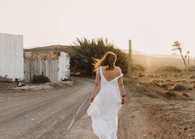 Woman in white dress in dry field in sunlight