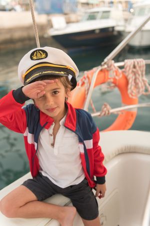 Child sitting on deck of yacht near quay