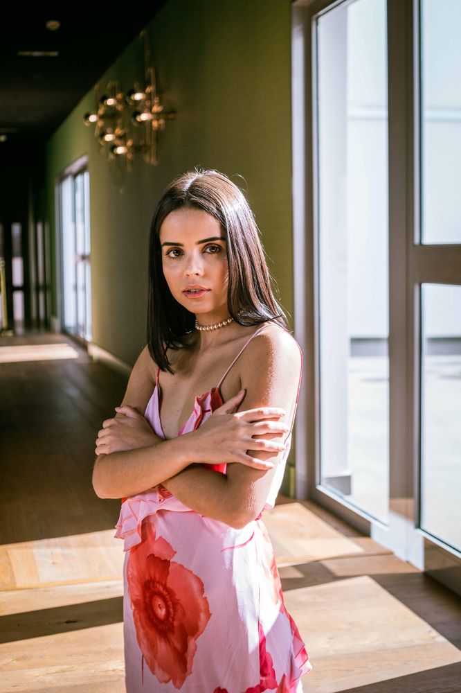 Stylish young woman in dress posing in room