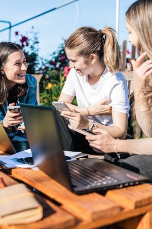 College students taking a break from studying showing messages on phones while talking and laughing.