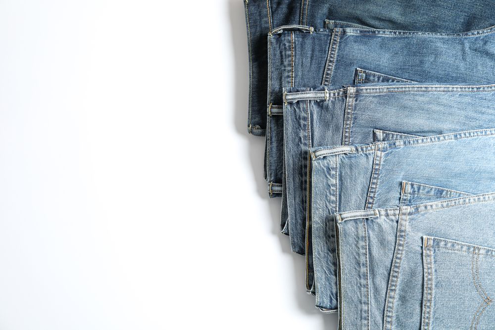 Jeans of different colors isolated on light background, space for text