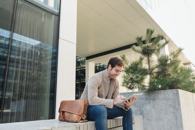 Smiling businessman using tablet on street