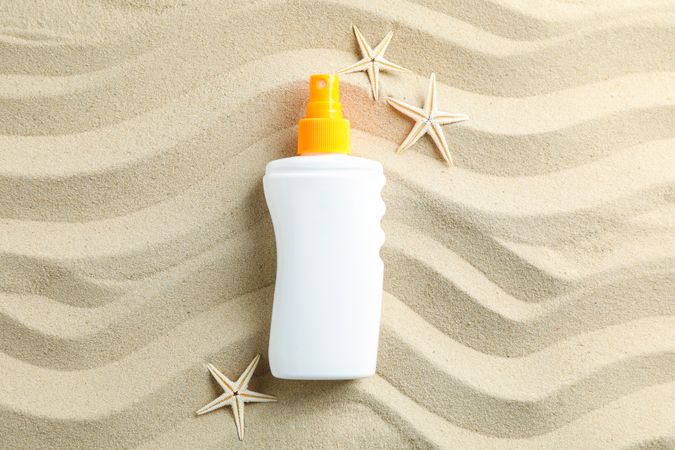Clear sea sand with sunscreen and starfishes, space for text. Summer vacation background
