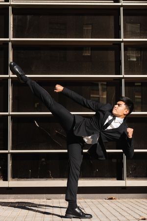 Businessman performing kick in air in street