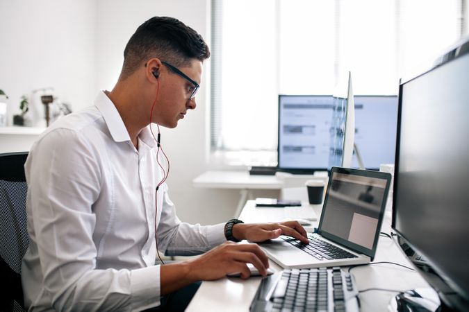 Man wearing spectacles working on laptop computer in office