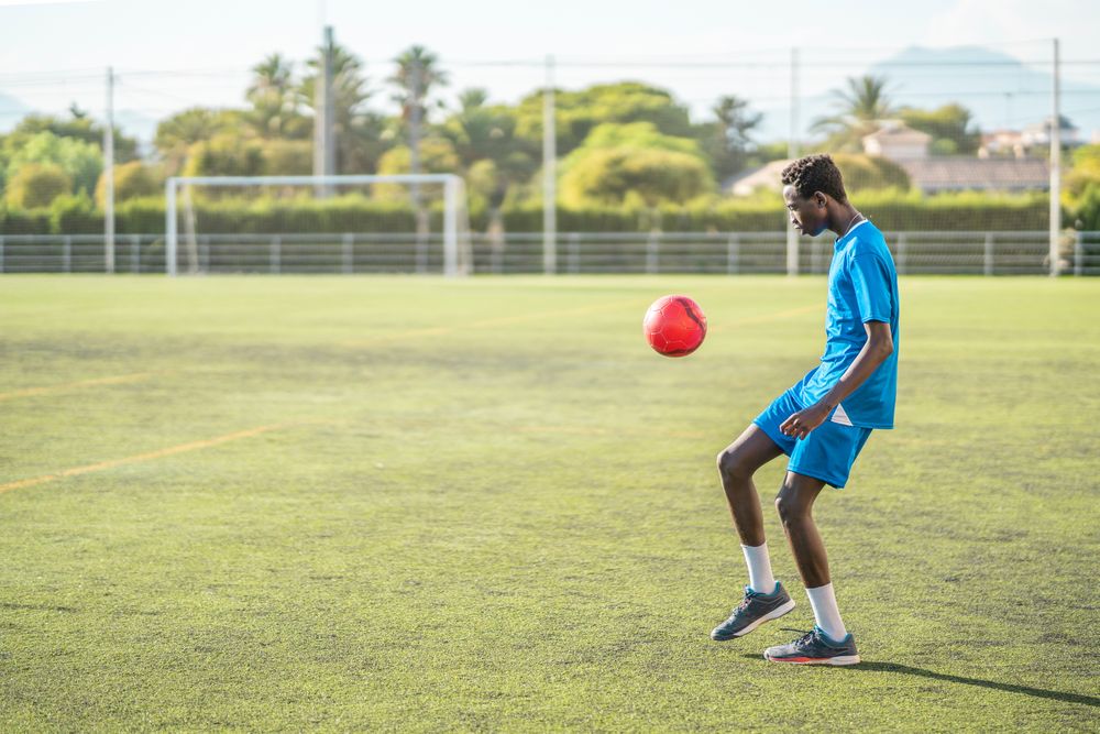 Black teenager juggling football ball