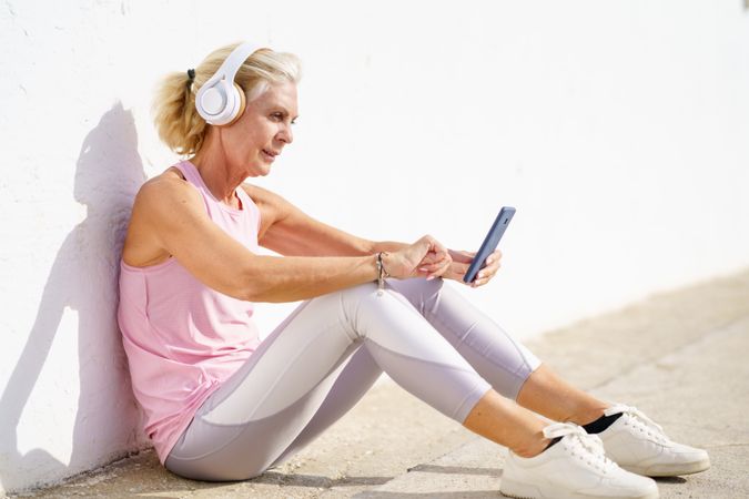 Mature female in sportswear texting on pier