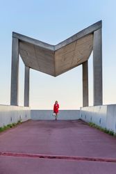 Woman in red coat walking towards modern gazebo