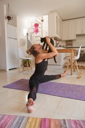 Flexible woman doing wide splits with cat at home