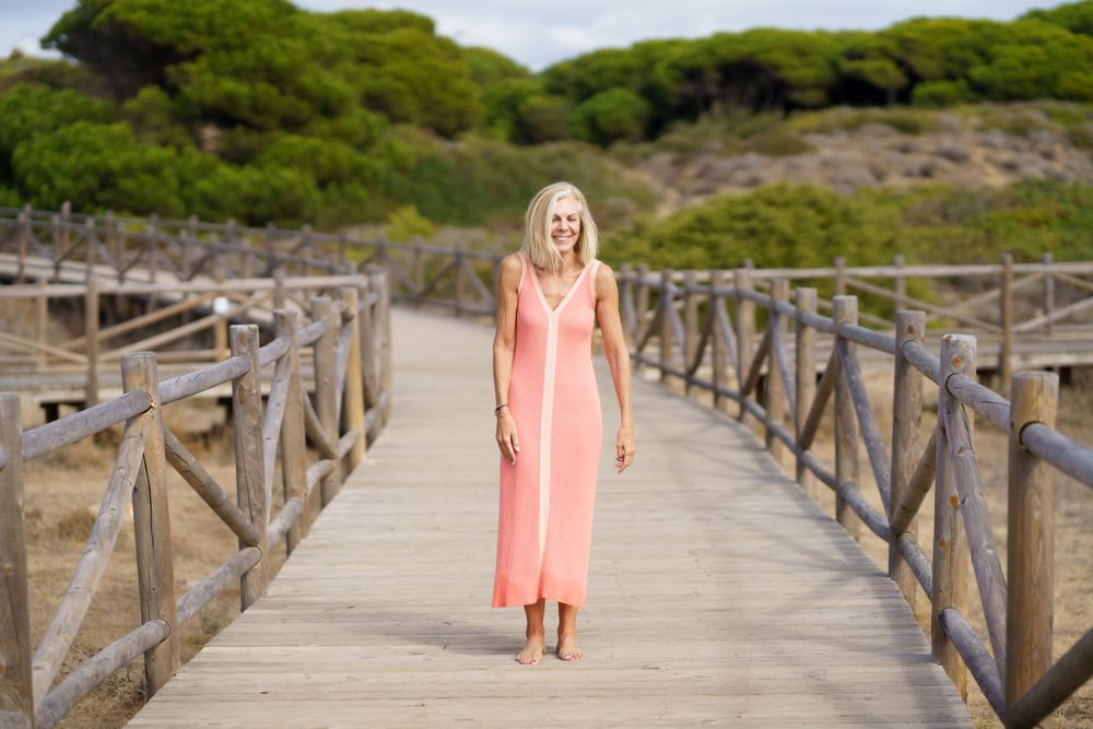 Mature female with grey hair going for a stroll on wooden walkway near the coast
