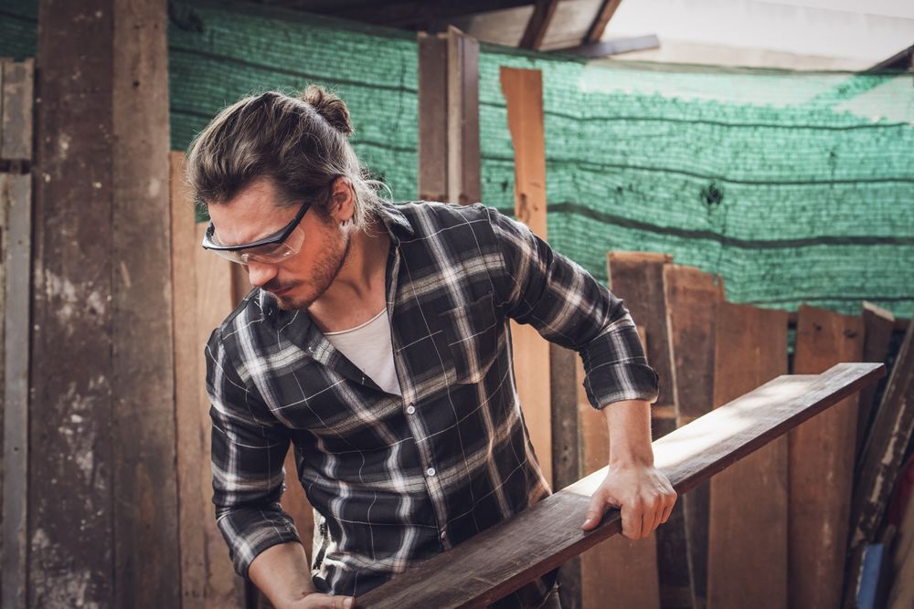 Male carpenter checking quality of the wood board before using it in carpentry workshop