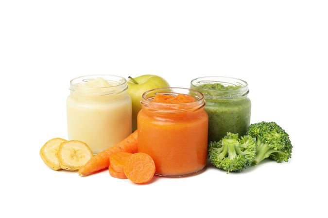 Glass jars with healthy baby food isolated on plain background