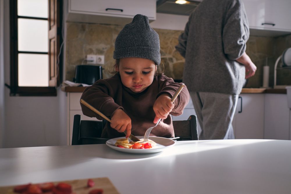 Little boy eating pancake with banana and strawberry