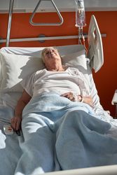 Ill woman sleeping on medical bed in hospital