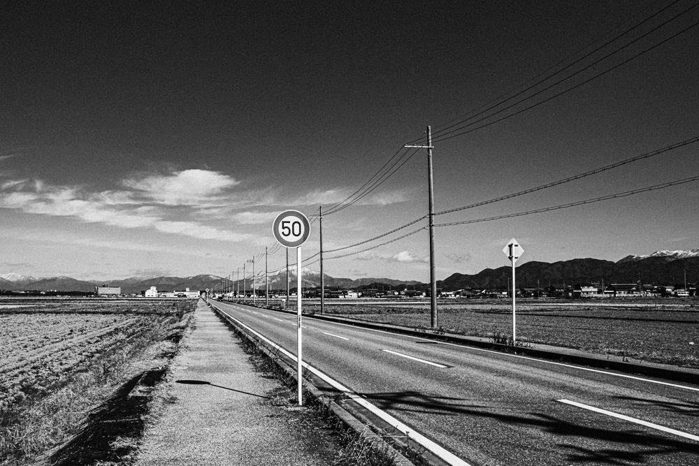 Grayscale photo of an asphalt road