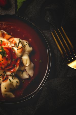 Plate of delicious ravioli with tomato sauce served on table