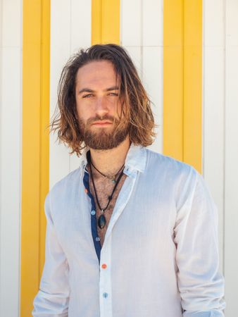 Cheerful guy standing near striped wall