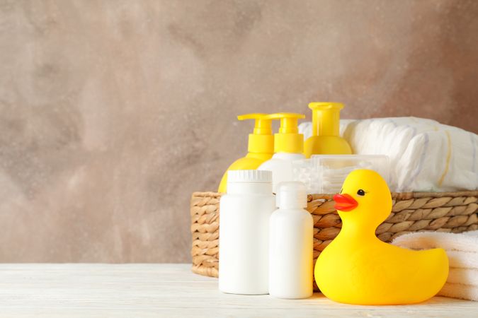 Baby hygiene accessories on wooden table against brown background