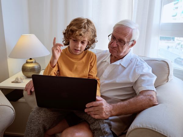 Grandfather with boy watching video on laptop