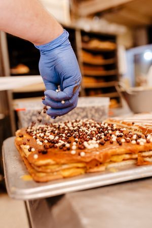 Anonymous baker spreading sprinkles on pastry