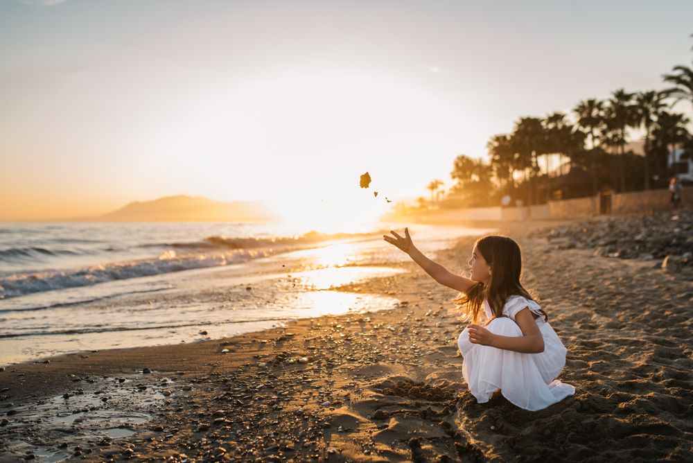 Adorable girl playing on seaside at sunset